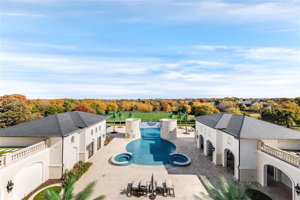 A wide angle view of the backyard showcasing the pool, turfed yard, and trees.