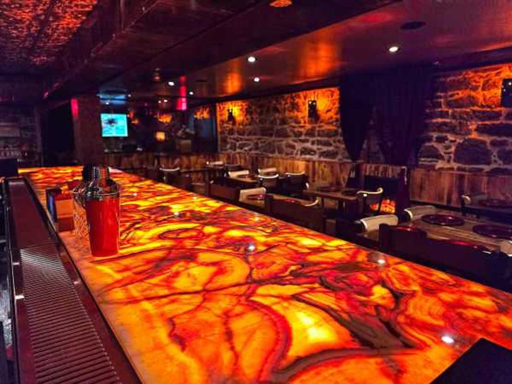 Exposed stone walls and a backlit glowing bar anchor the subterranean space at Red: Italian.