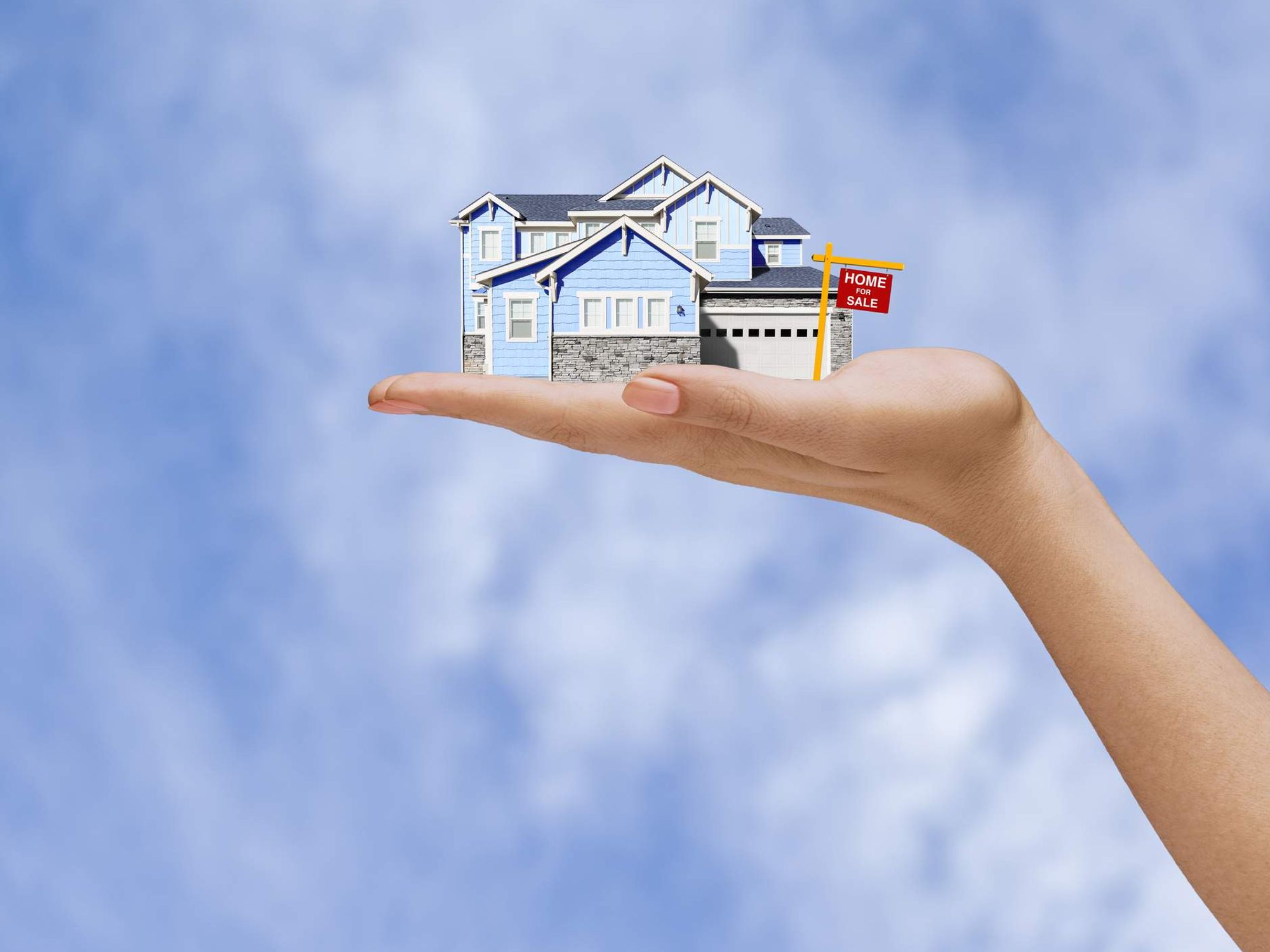 Hand of woman holding home for sale in sky