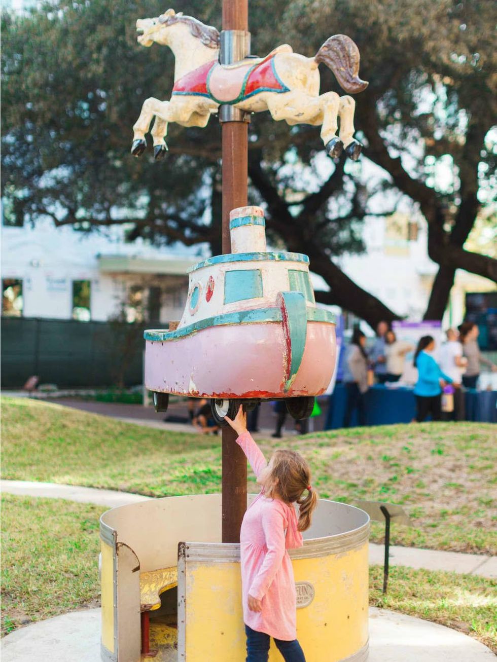 Little girl pointing at a carousel sculpture