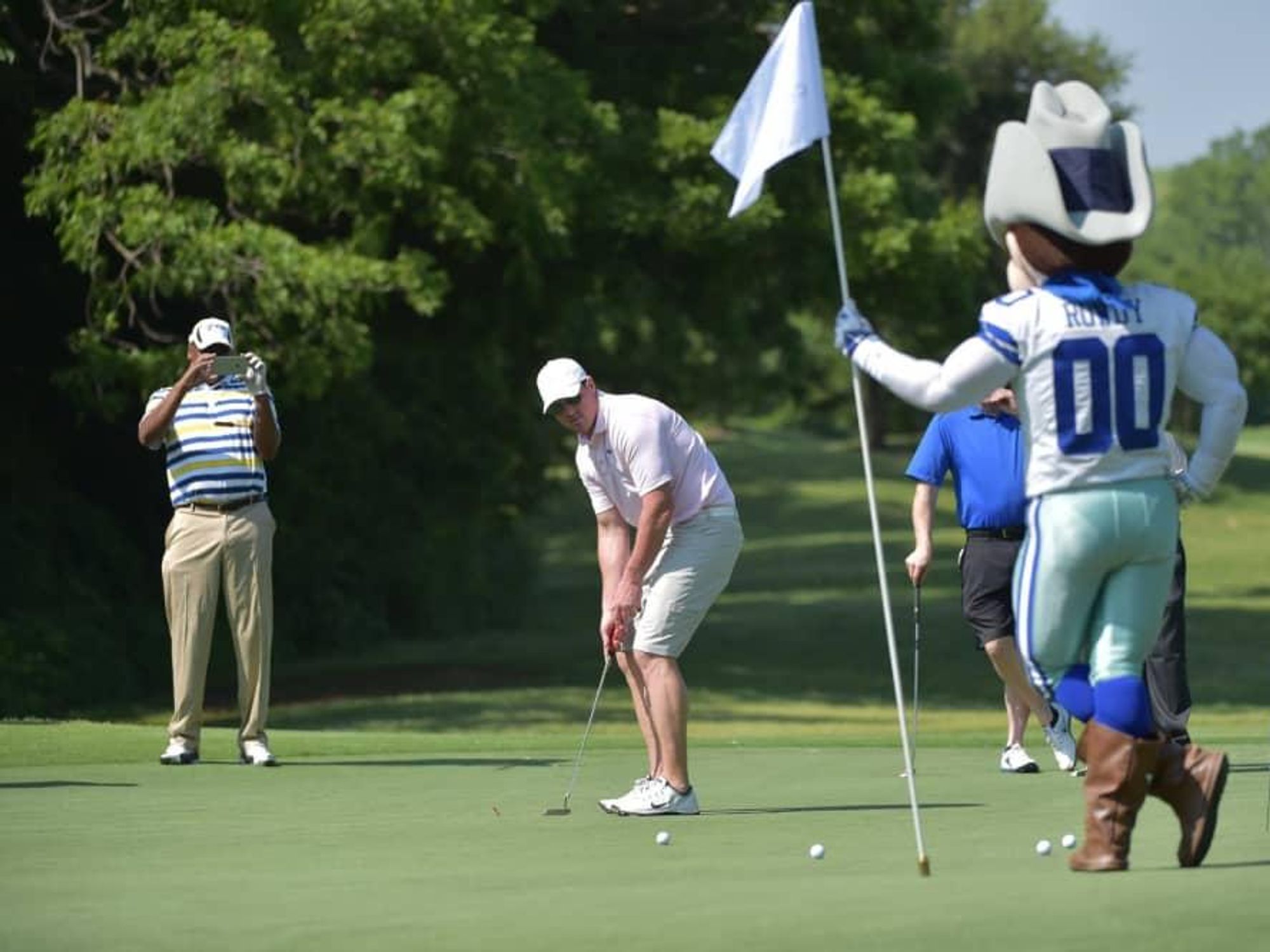 Men playing golf with Rowdy mascot