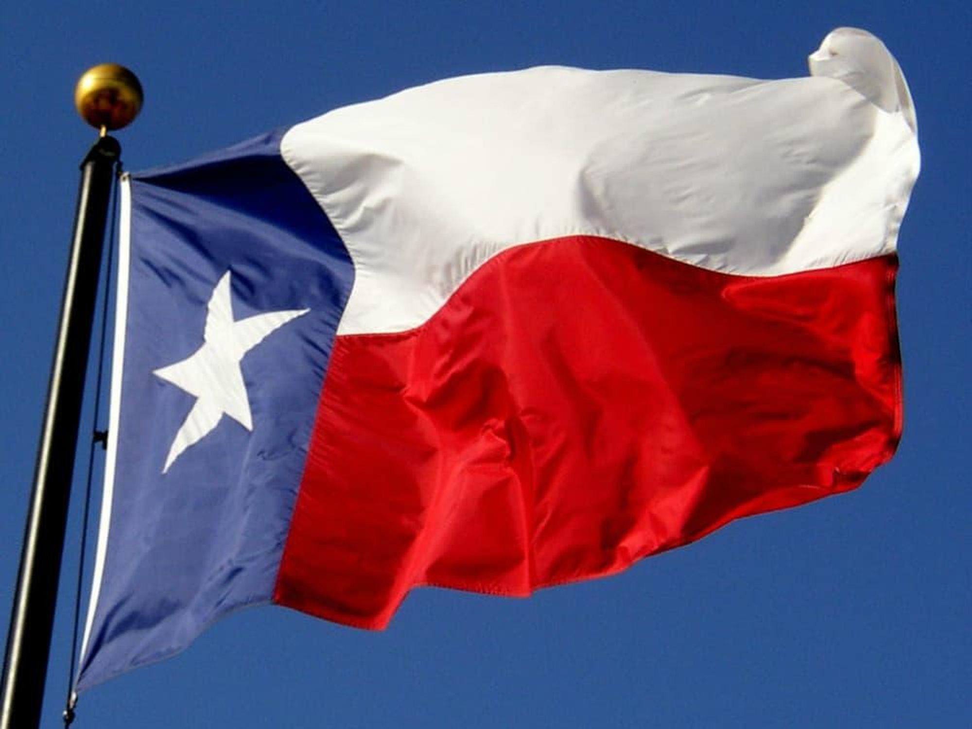 Texas flag flying with blue sky in background