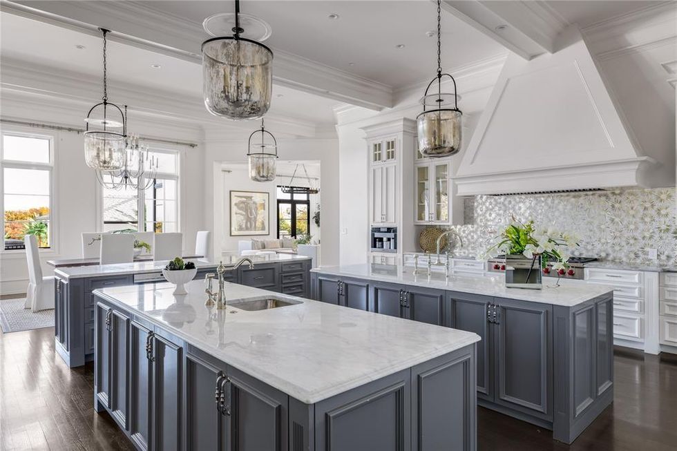 The chef's kitchen with grey cabinets and white countertops.