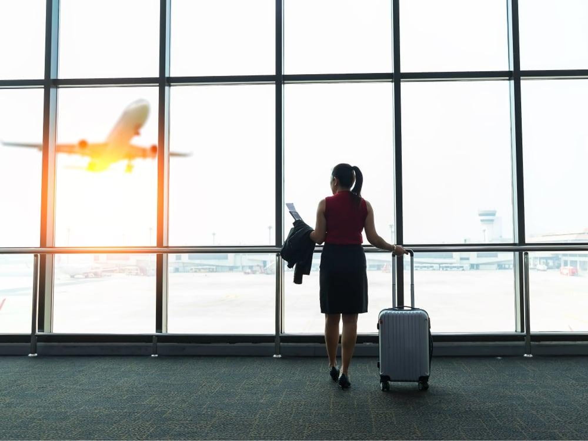 Woman at airport watching an airplane take off